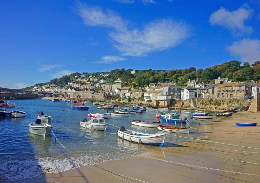 A beach with boats pulled up onto it and a blue sky