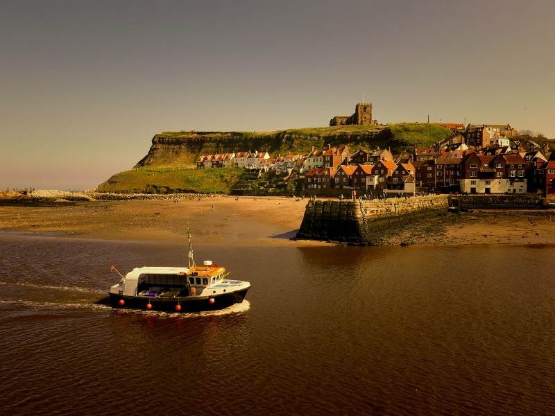 A boat and an abbey on a hill in the background