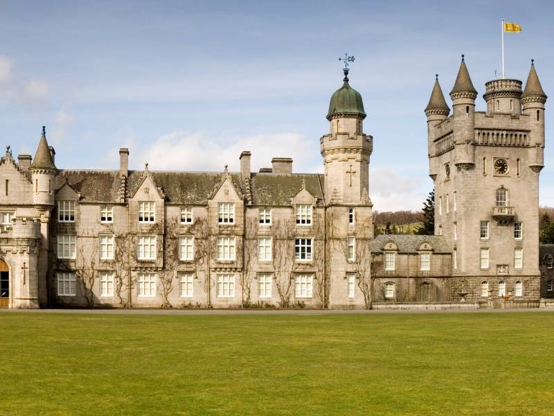 A castle with a flag with green lawns in front of it