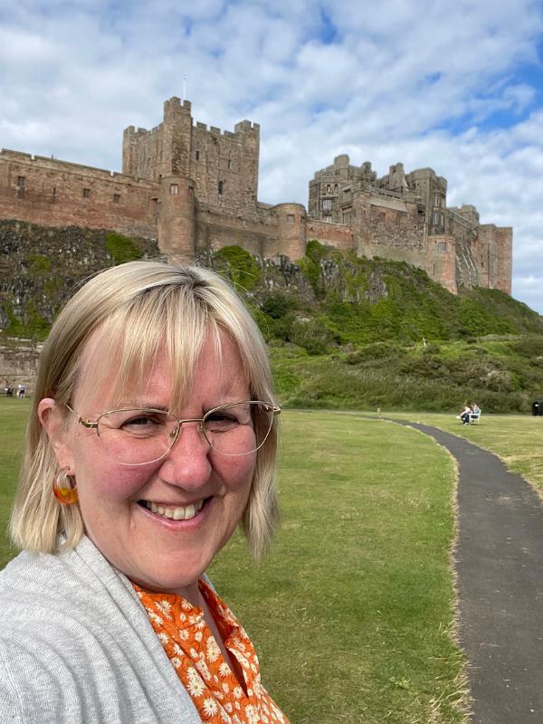 A lady in front of a castle.
