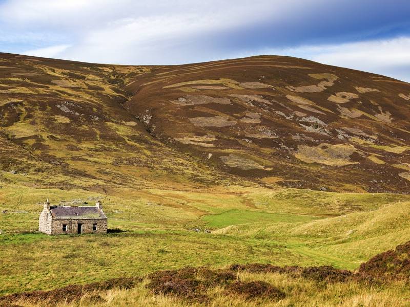 A lone stone house surrounded by hills