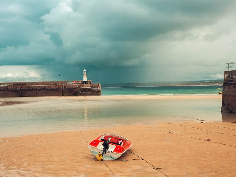 A picture of a red boat on a beach