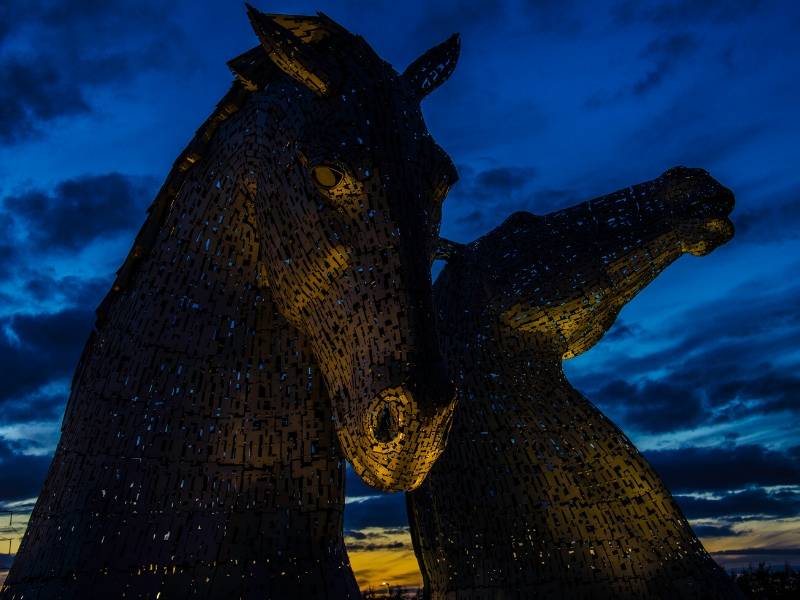 Two statues of horses heads against the night sky