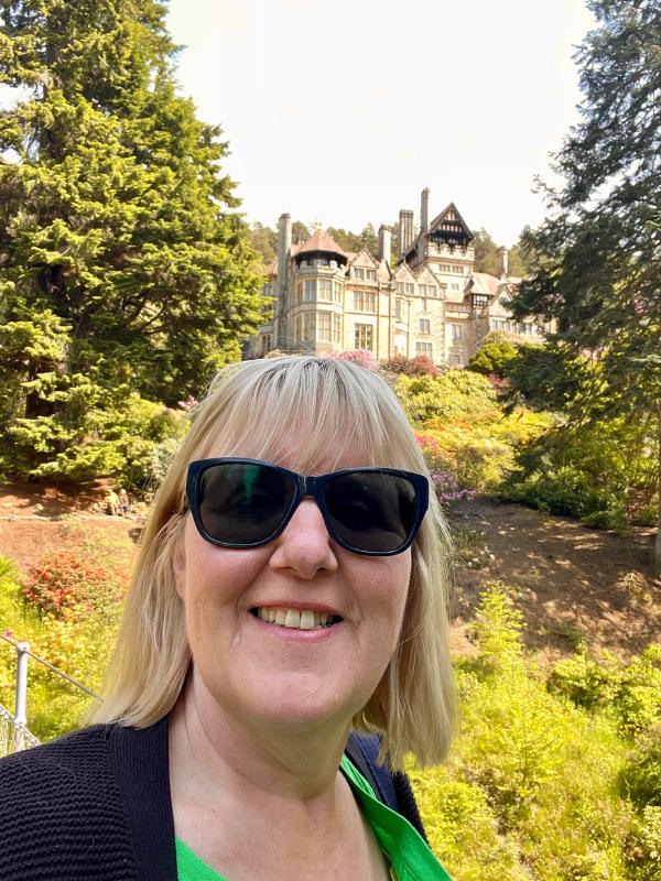 A stately home with lady in front.