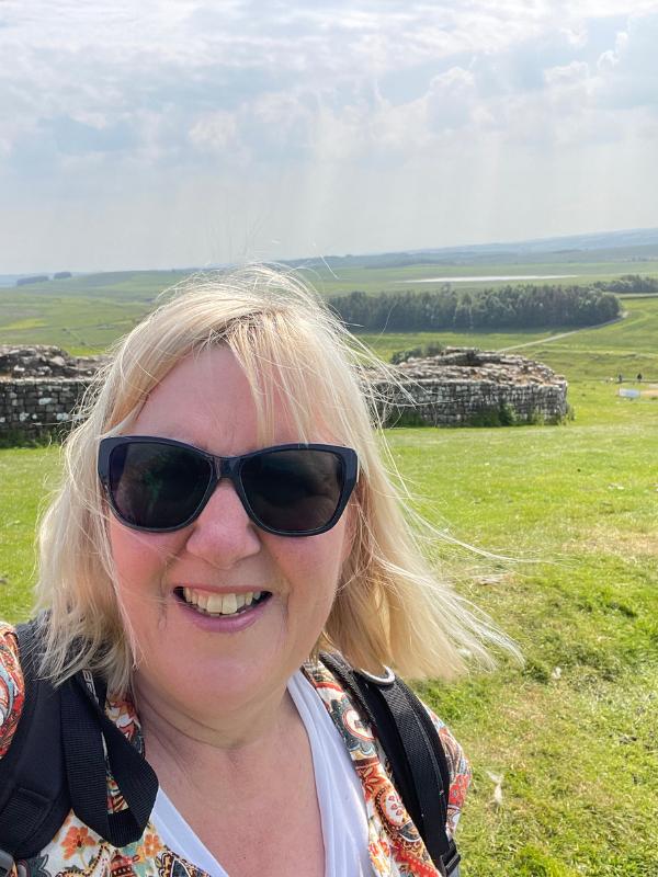 A lady with countryside behind.