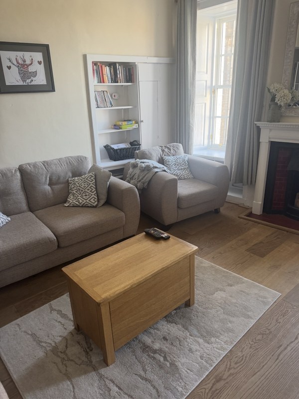 The living room of a Grassmarket apartment in Edinburgh with sofas, a fireplace and a tall sash window