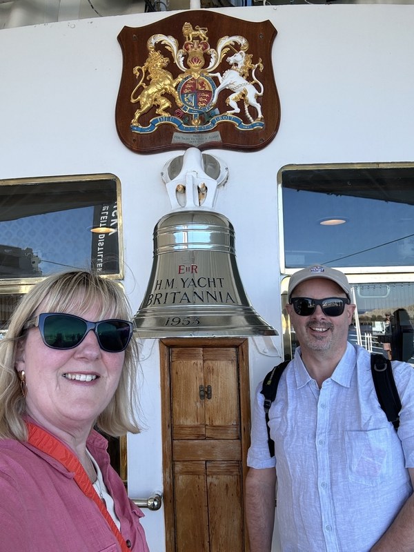 Tracy and Doug beside the ship's bell on the Royal Yacht Britannia at Ocean Terminal in Leith