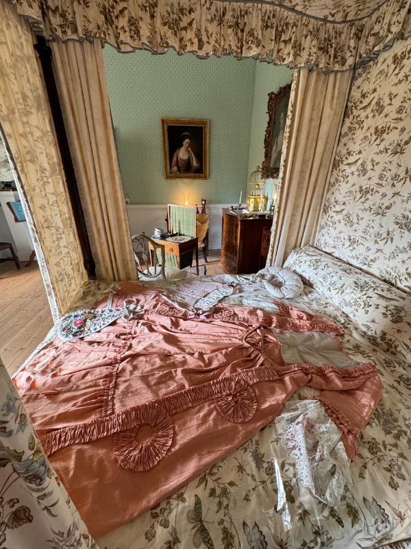 a bed with curtains and a picture of a woman