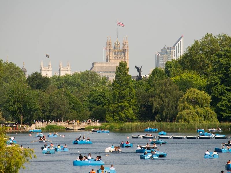 Hyde Park in London with people enjoying the summer and sailing on the lake.