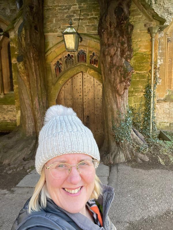 Lady in front of a door with trees on either side.