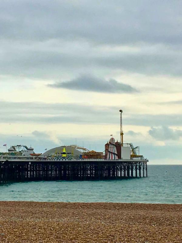 Brighton Palace Pier with helter skelter and rides seen from the pebble beach