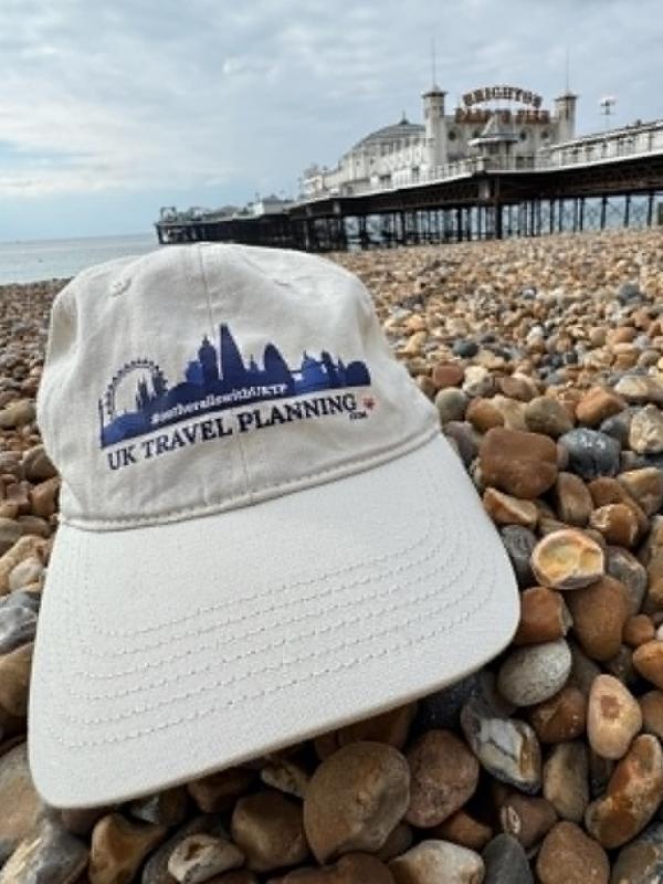UK Travel Planning cap on Brighton's pebble beach in front of Brighton Palace Pier