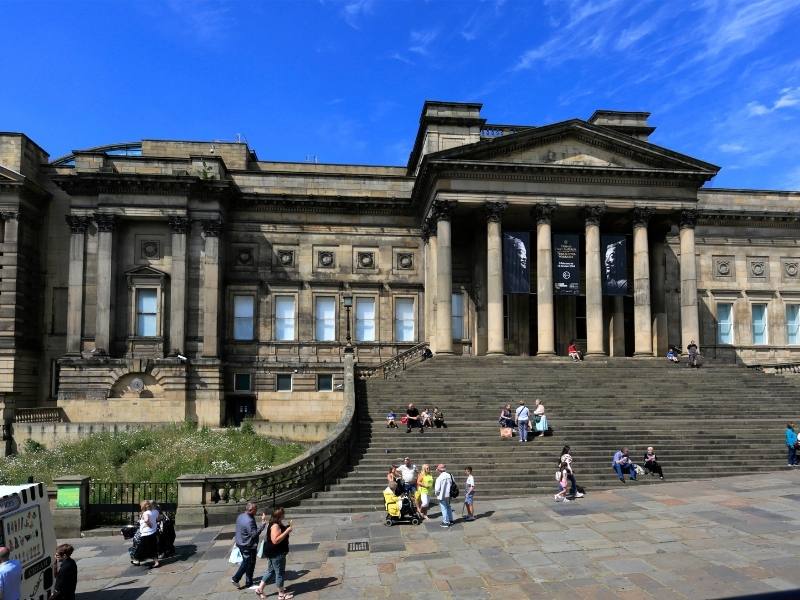 The World Museum in Liverpool and people sitting on the steps of the building