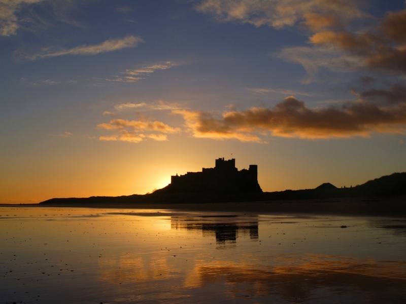 Bamburgh Castle at sunset can be seen from some Northumberland Coastal Cottages.