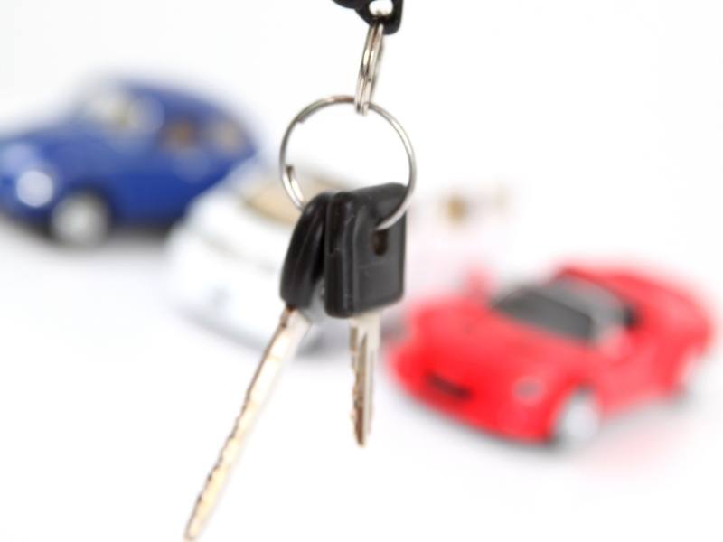 Bunch of car keys with red and blue cars in the background.