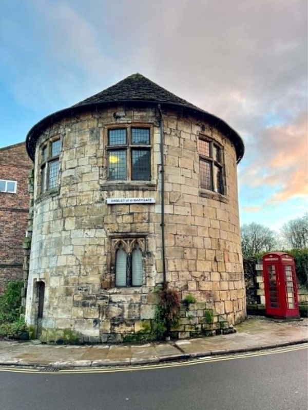 Medieval stone tower and red telephone box on Marygate, York