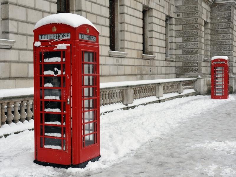 Red phone boxes covered in snow in London.