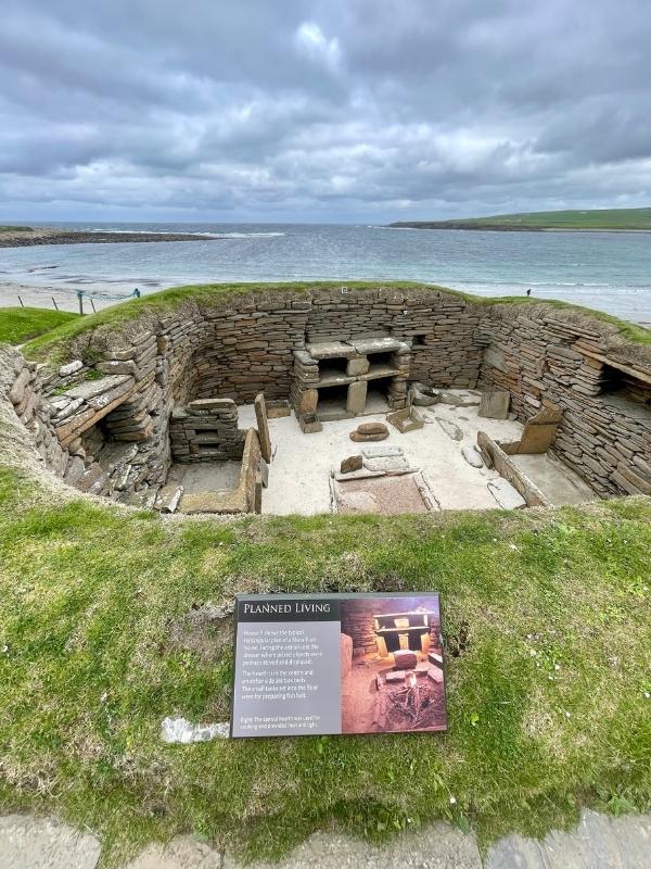 View of Skara Brae with the sea and beach behind.