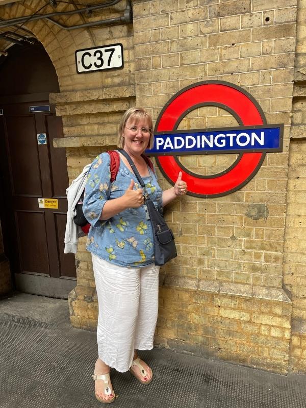 Woman standing near Paddington Station sign.