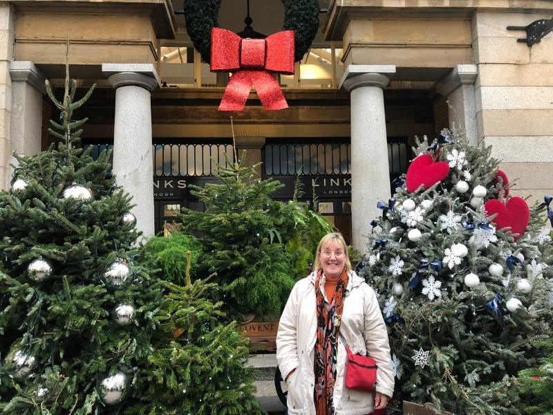 Woman standing in front of Christmas decorations.