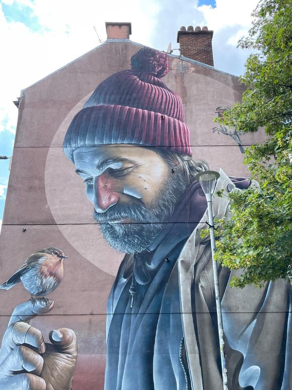 Many places to stay in Glasgow have interesting street art near such as this art of a man holding a robin.