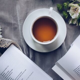 Cup of tea on a table with books and flowers - UK Travel Planning Book Club