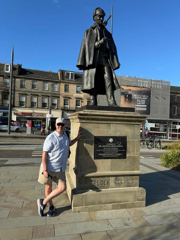 Episode 119 Doug standing in front of a statue.