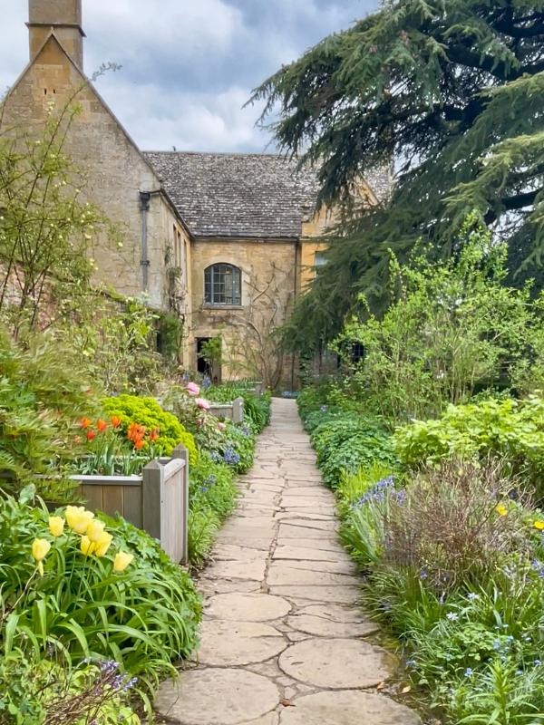 Accessible travel UK — a beautiful but uneven stone path through a Cotswolds garden, typical of the surfaces visitors may encounter in historic gardens