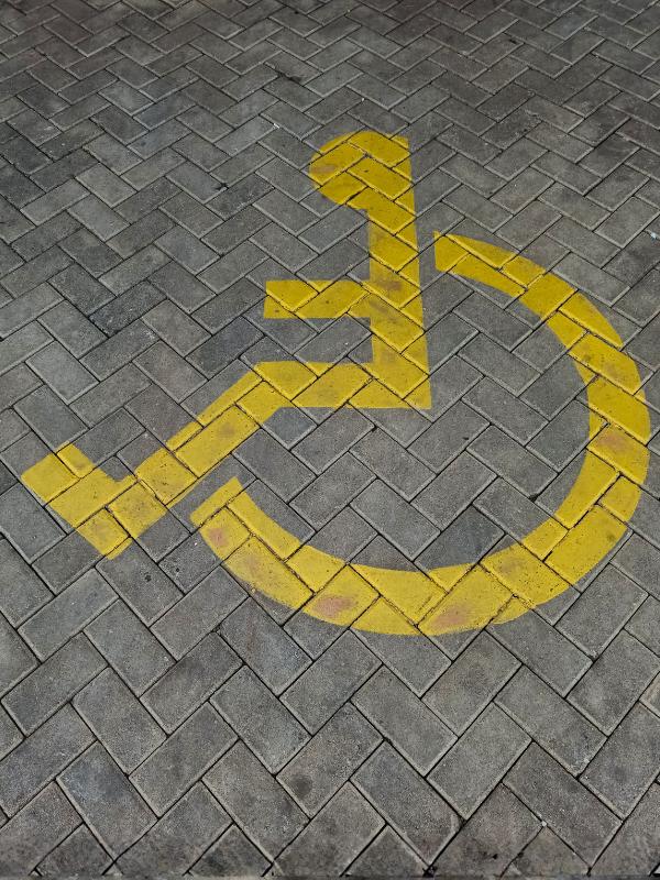 Accessible travel UK — yellow wheelchair symbol on paving stones marking a disabled parking bay in the UK