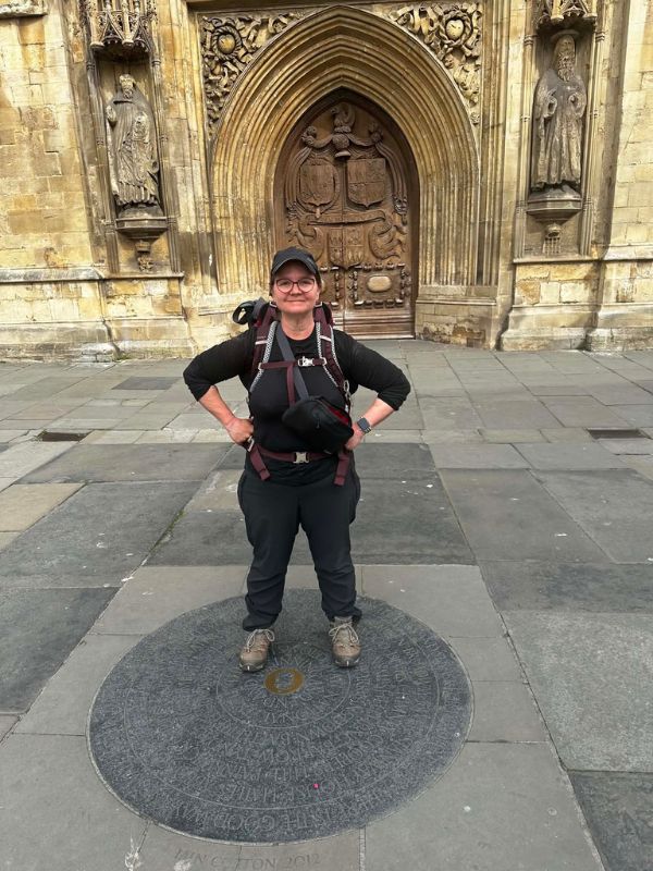 Katherine standing on the Cotswold Way marker plaque outside Bath Abbey at the end of the walk