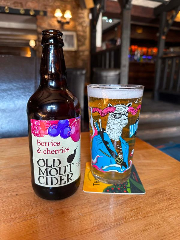 A bottle and glass of cider on a wooden table in a Cornish pub