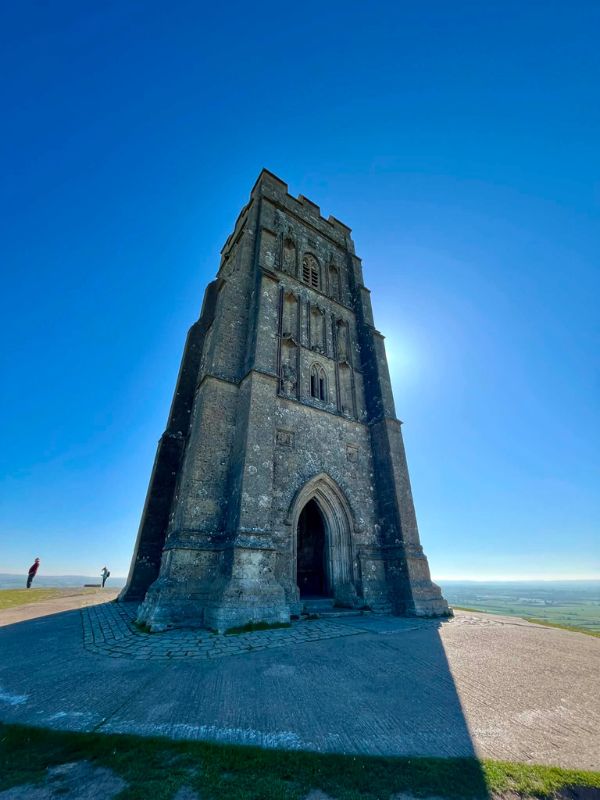 St Michael's Tower on top of Glastonbury Tor against a clear blue sky