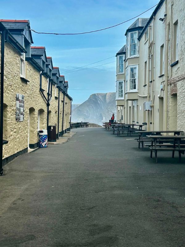 Stone buildings and picnic benches at Hartland Quay in Devon with dramatic cliffs beyond