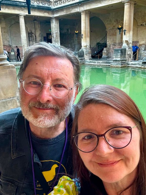 Katherine and Glen taking a selfie beside the green water of the Roman Baths in Bath