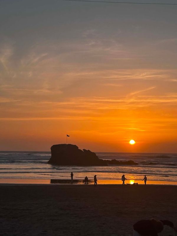 Sunset over Perranporth beach with Chapel Rock silhouetted against an orange sky