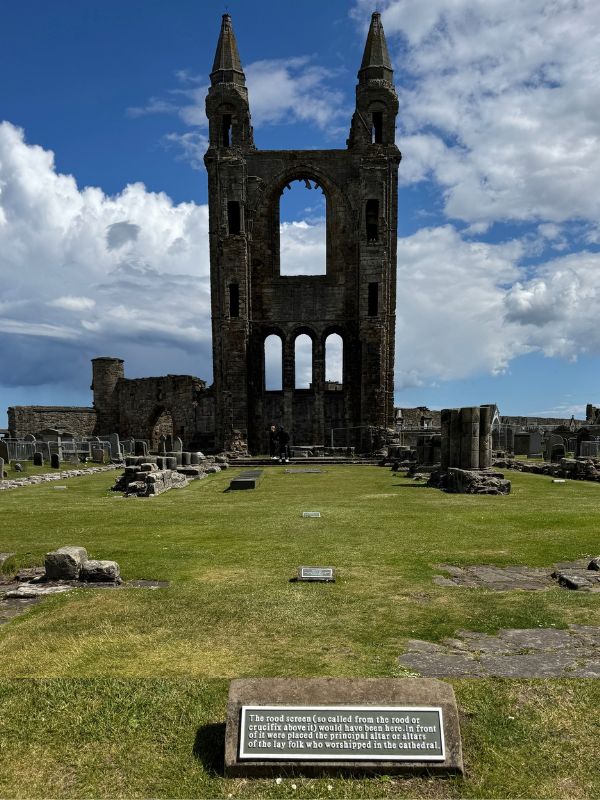St Rule's Tower and the graveyard at St Andrews Cathedral, framed by a ruined arch.