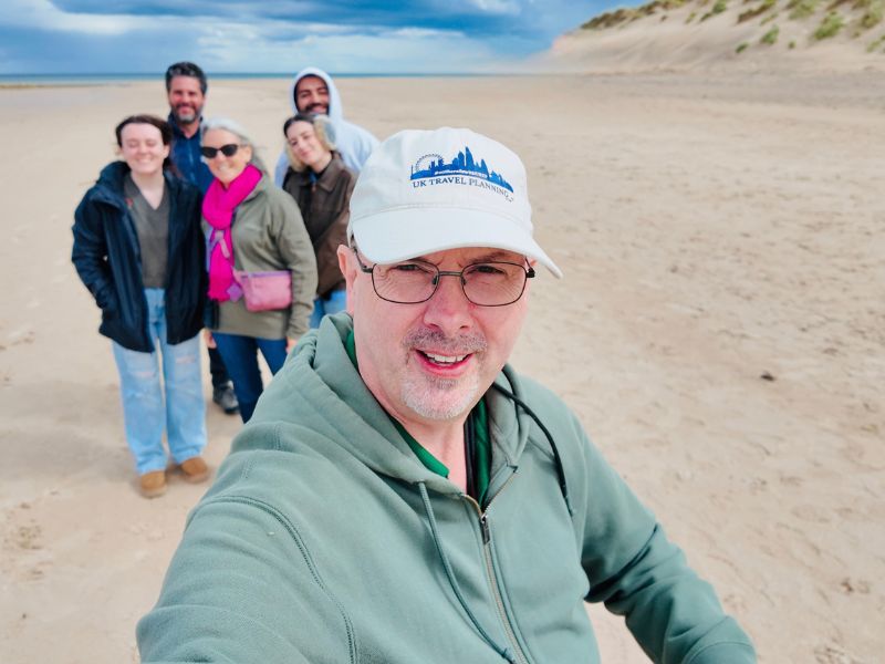Doug's Rabbie's tour group on the beach at Bamburgh with the castle behind
