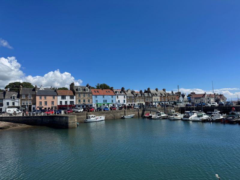 Boats moored in Anstruther harbour in front of a row of colourful seafront houses
