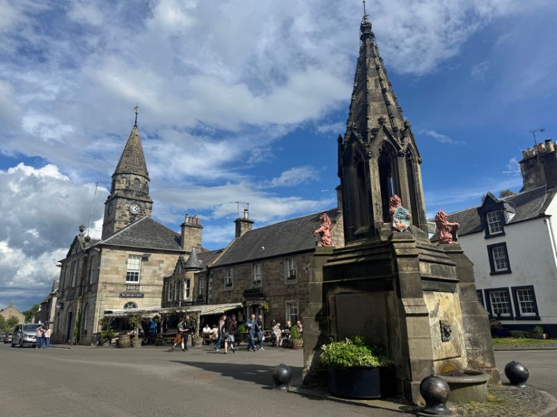 The Bruce Fountain with its carved heraldic figures in the centre of Falkland, with the town hall clock spire behind