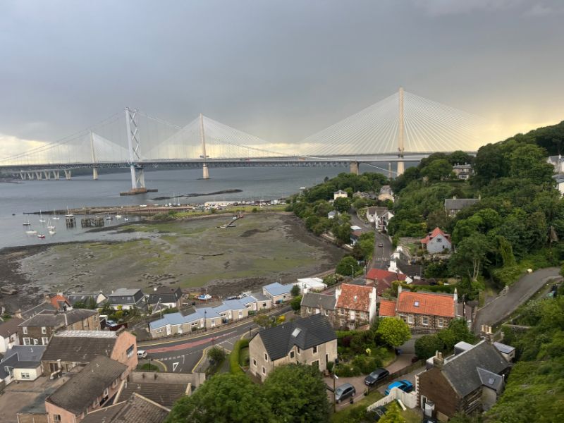 The Forth Road Bridge and Queensferry Crossing spanning the Firth of Forth, seen from above the village rooftops