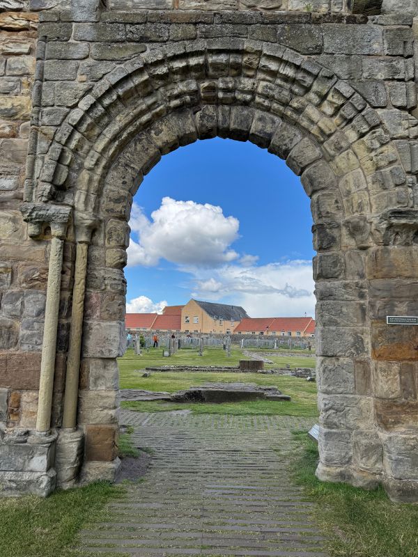 A rounded medieval stone archway looking into the grounds of St Andrews Cathedral