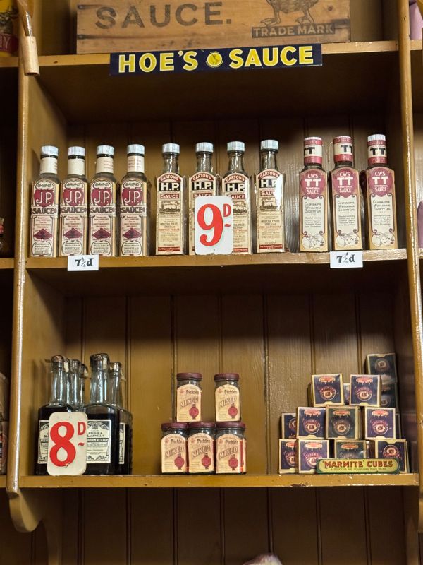 Bottles of HP Sauce, jars of pickles and Marmite cubes with old penny price tags in the Co-op grocery at Beamish Museum
